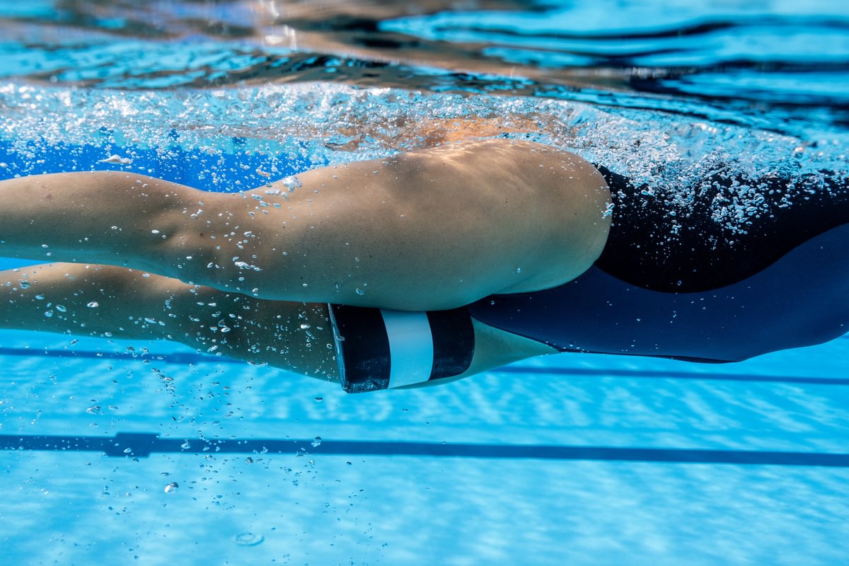 woman swim training in pool with orca pull buoy