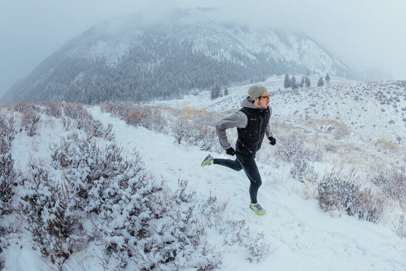 Man running in the snow in Hoka run clothing, run legging