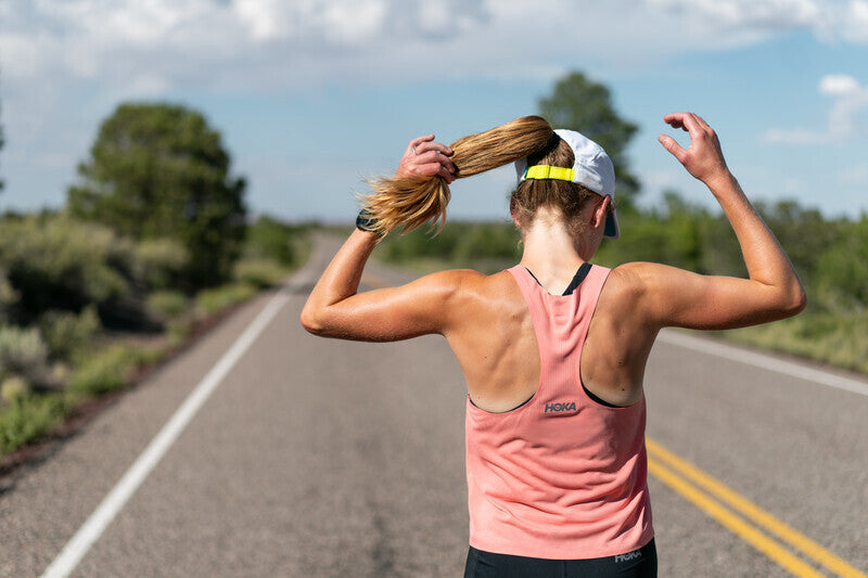 woman wearing HOKA race day singlet in pink running down country road