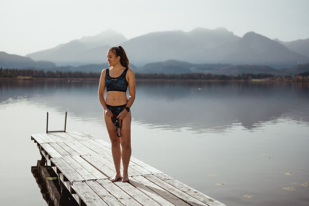 woman about to swim at lake wearing a black bikini from funkita, rip curl, orca