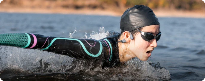 woman swimming with shokz openswim bone conduction headphones