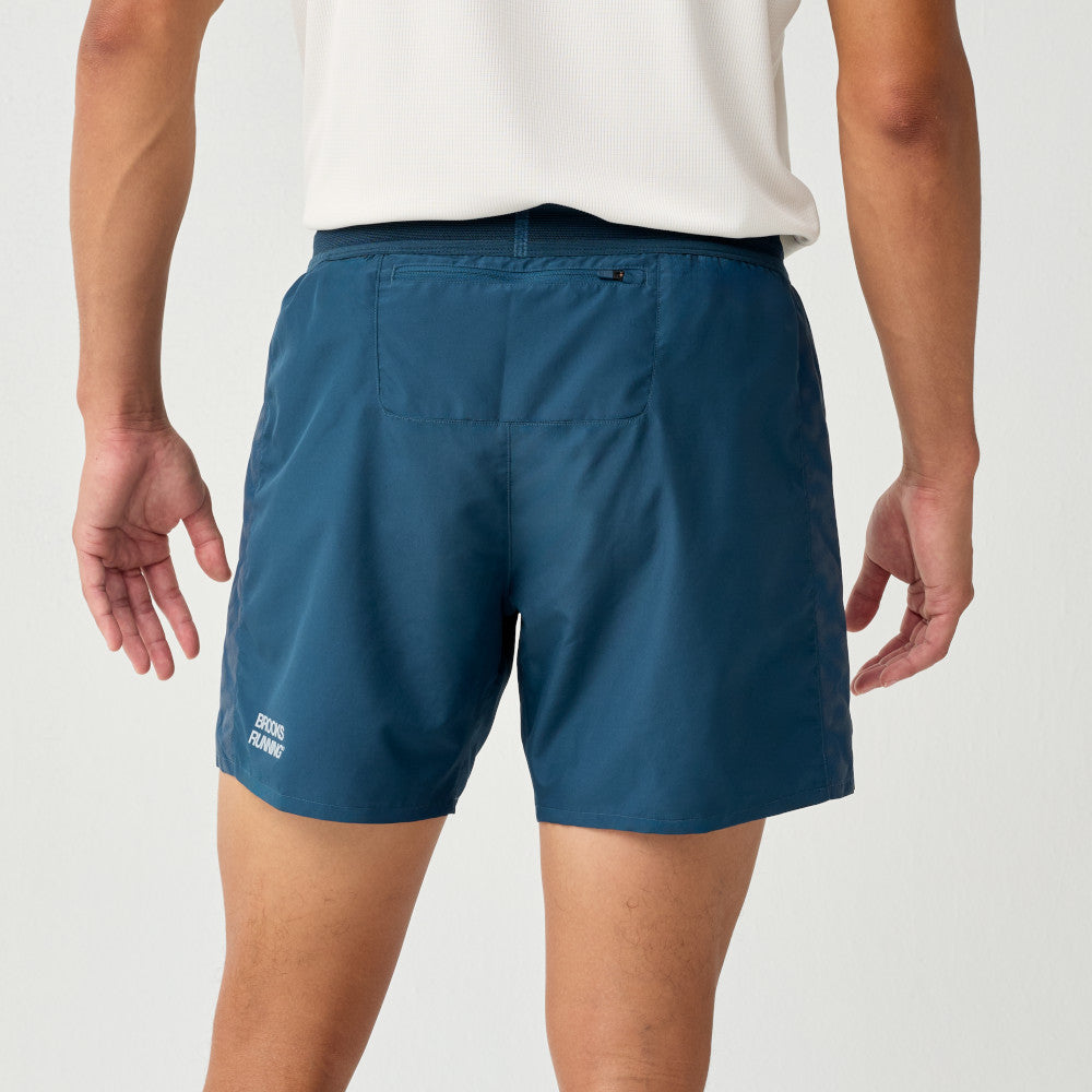 Man wearing Brooks Dash Reflective Shorts, showing back and back zip pocket, logo near hem