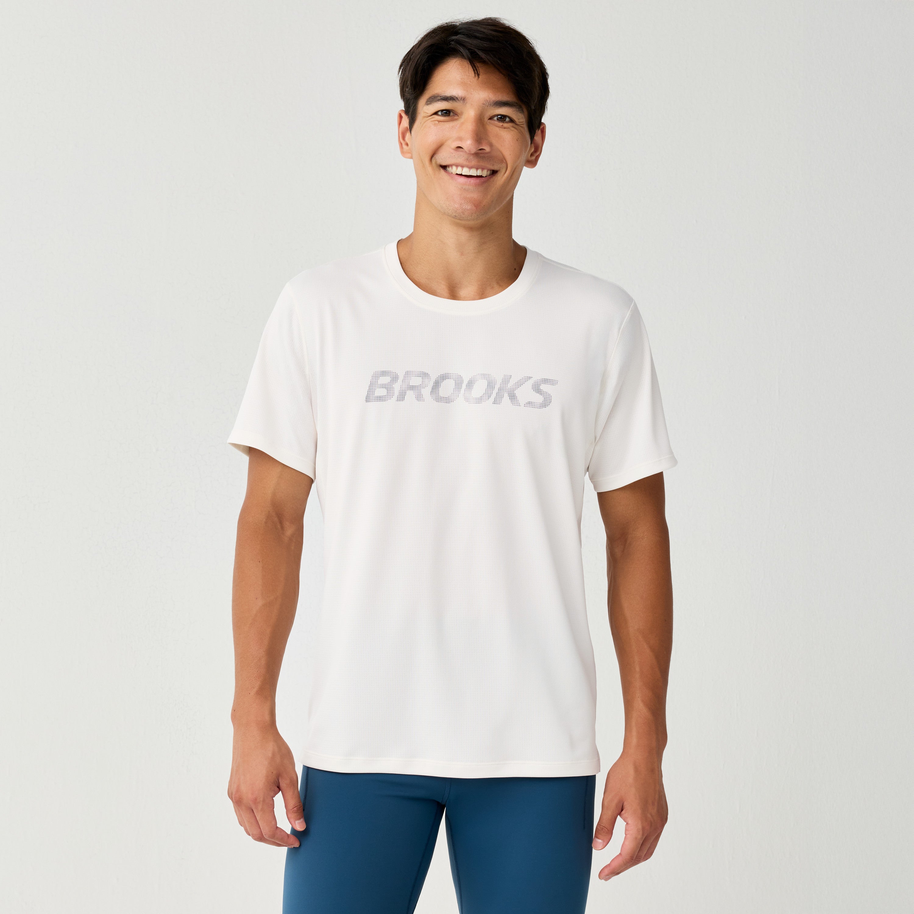 Man wearing Brooks Reflective Dash Tshirt in cream colour with reflective writing