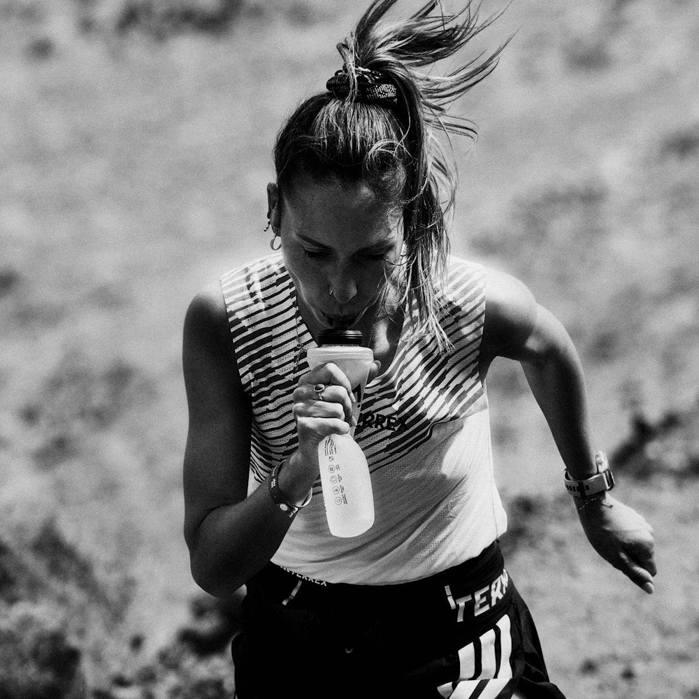 woman drinking maurten additions from soft flask whilst running 