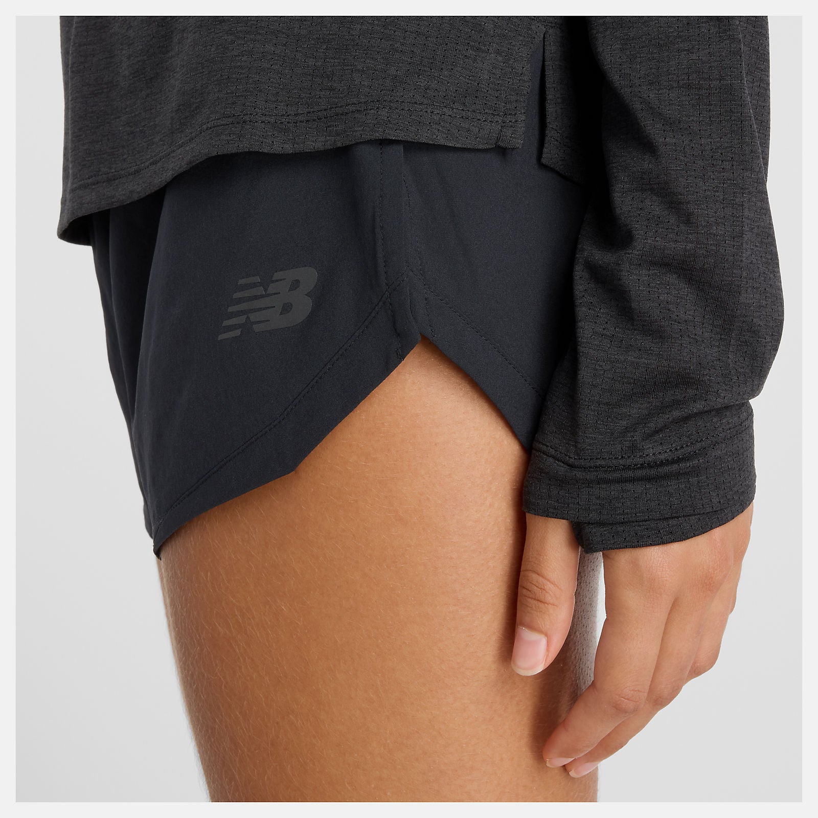 woman wearing NB athletics long sleeve run top in black, showing close up of pin dot mesh and thumbholes