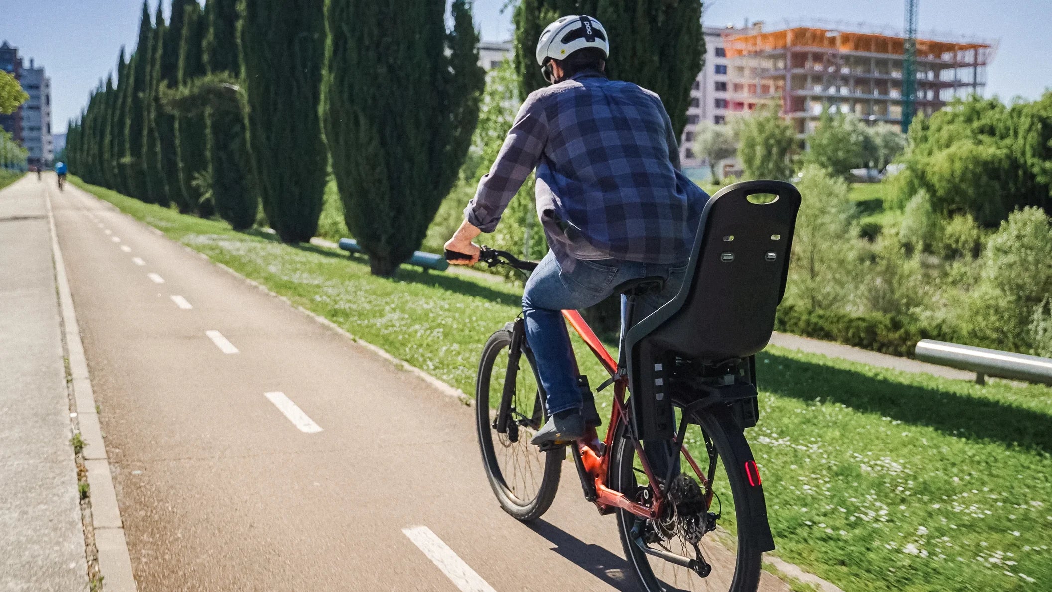Man cycling an orbea Kemen ADV ebike on a cycle path with child seat on back of bike