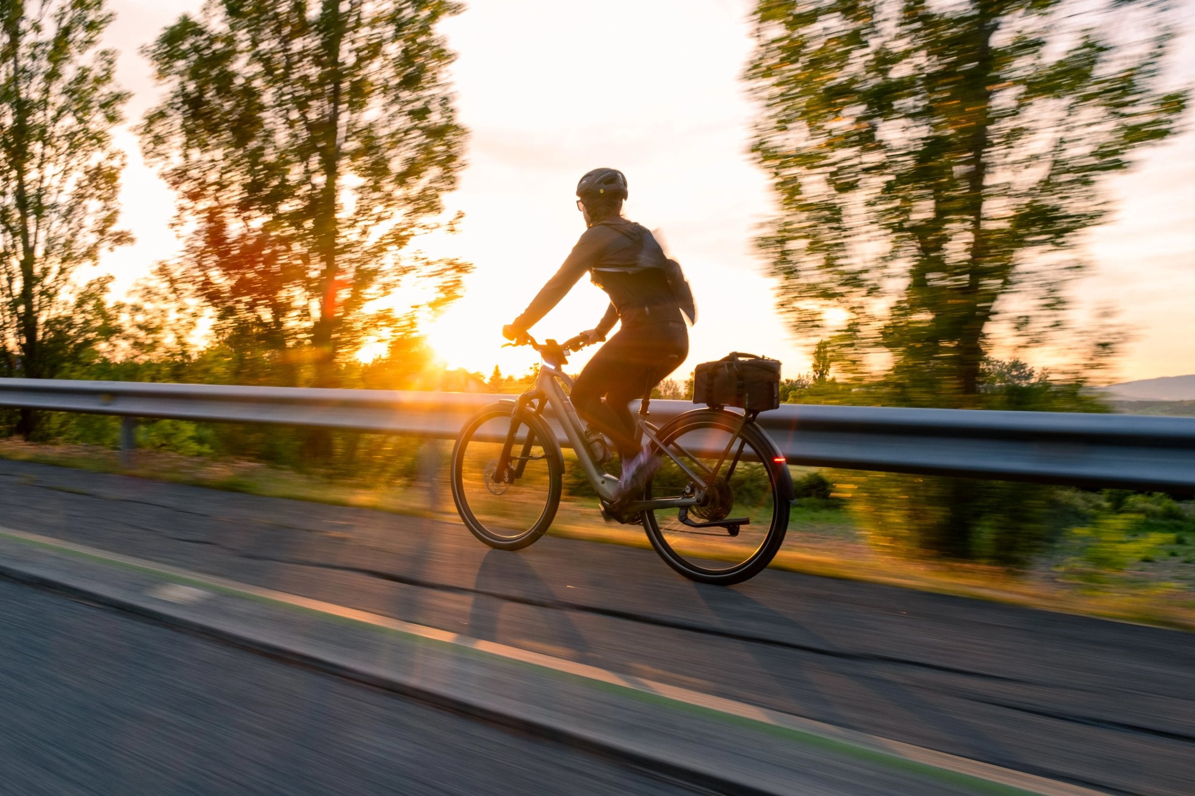 woman cycling an orbea kemen tour ebike on a road in evening sun