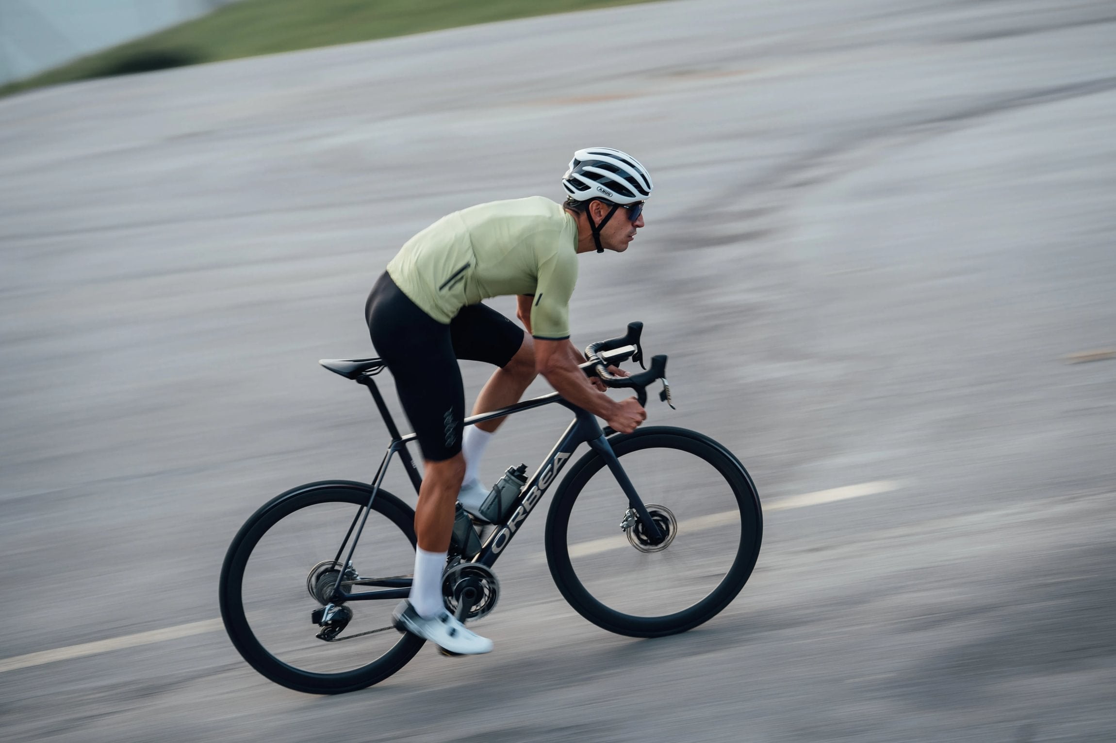 man cycling fast on road on an orbea orca road bike