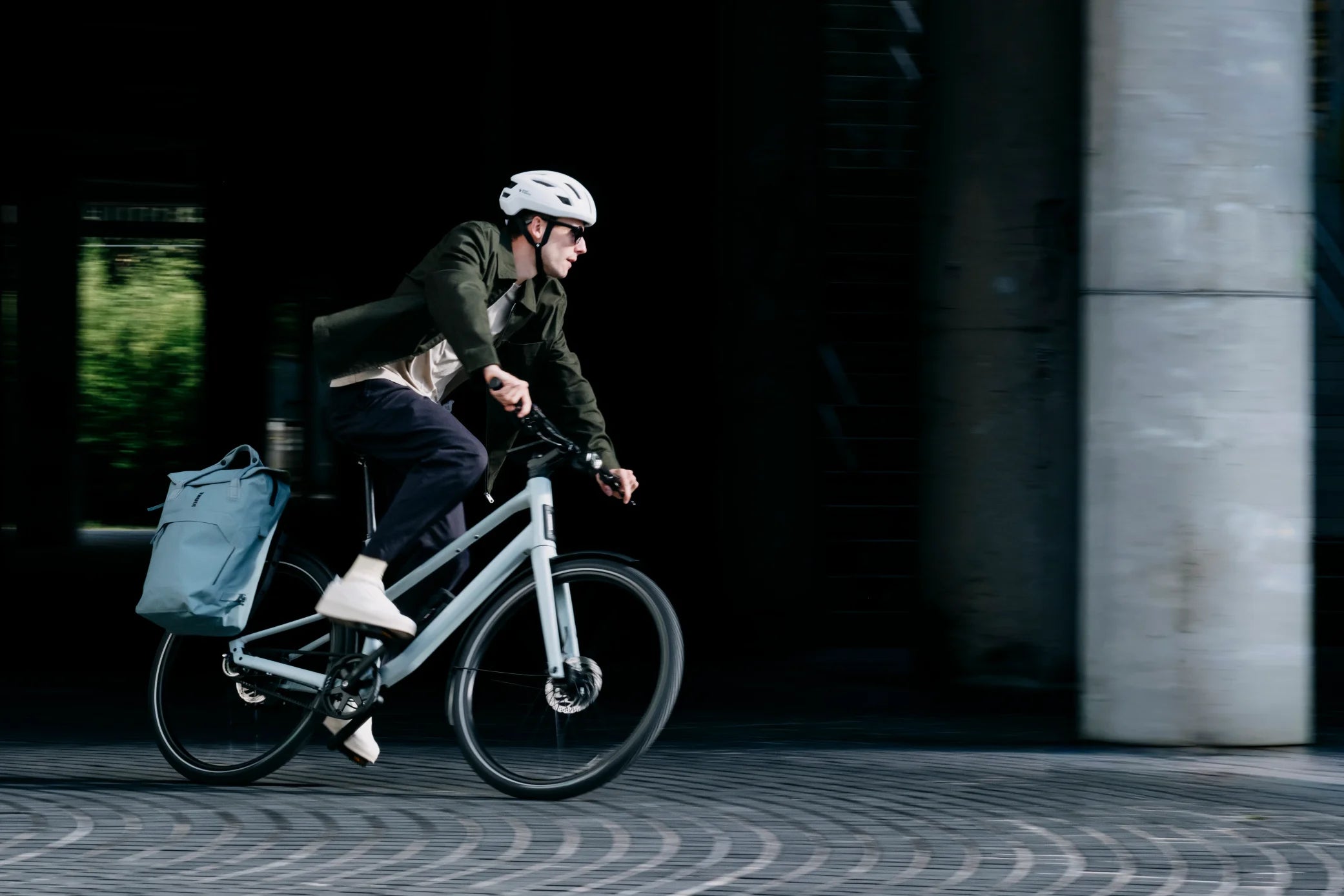 Man cycling the Orbea Vector 10 through the city with panniers attached to the bike
