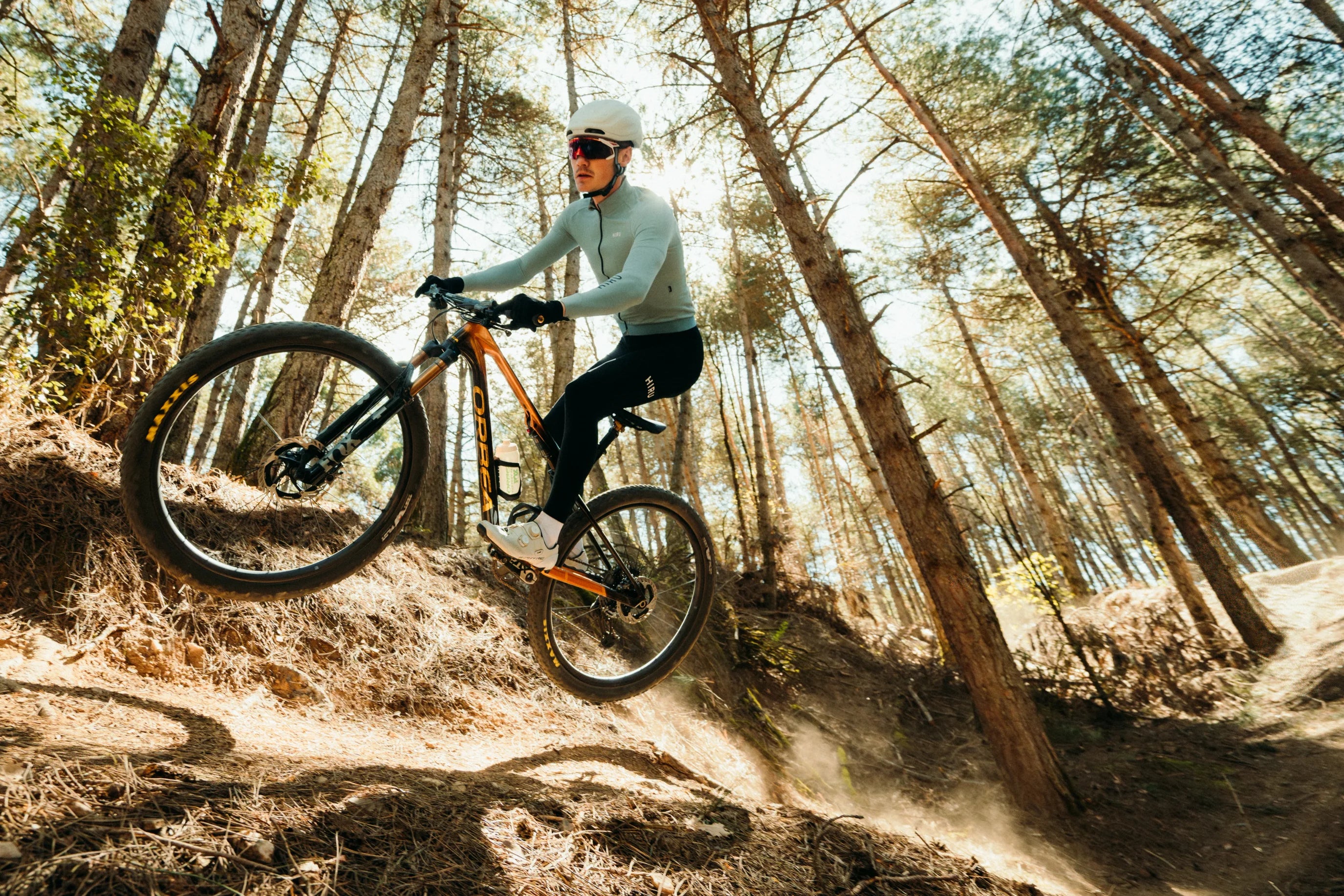 man riding orbea oiz through forest, cross country mountain bike