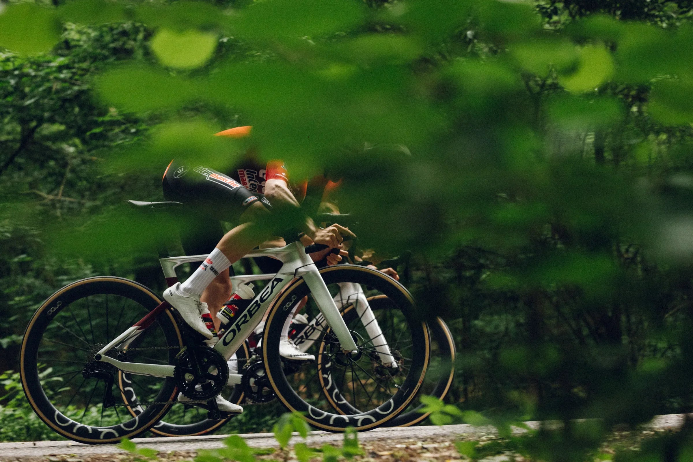 Cyclists riding Orbea Orca Aero bikes through the forest
