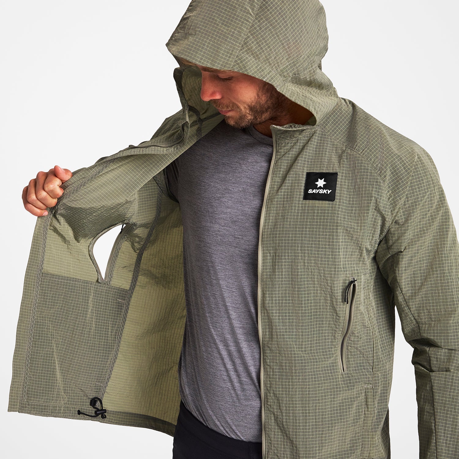 Man wearing SAYSKY clean hooded jacket for road running in beige colour showing ventilation pockets