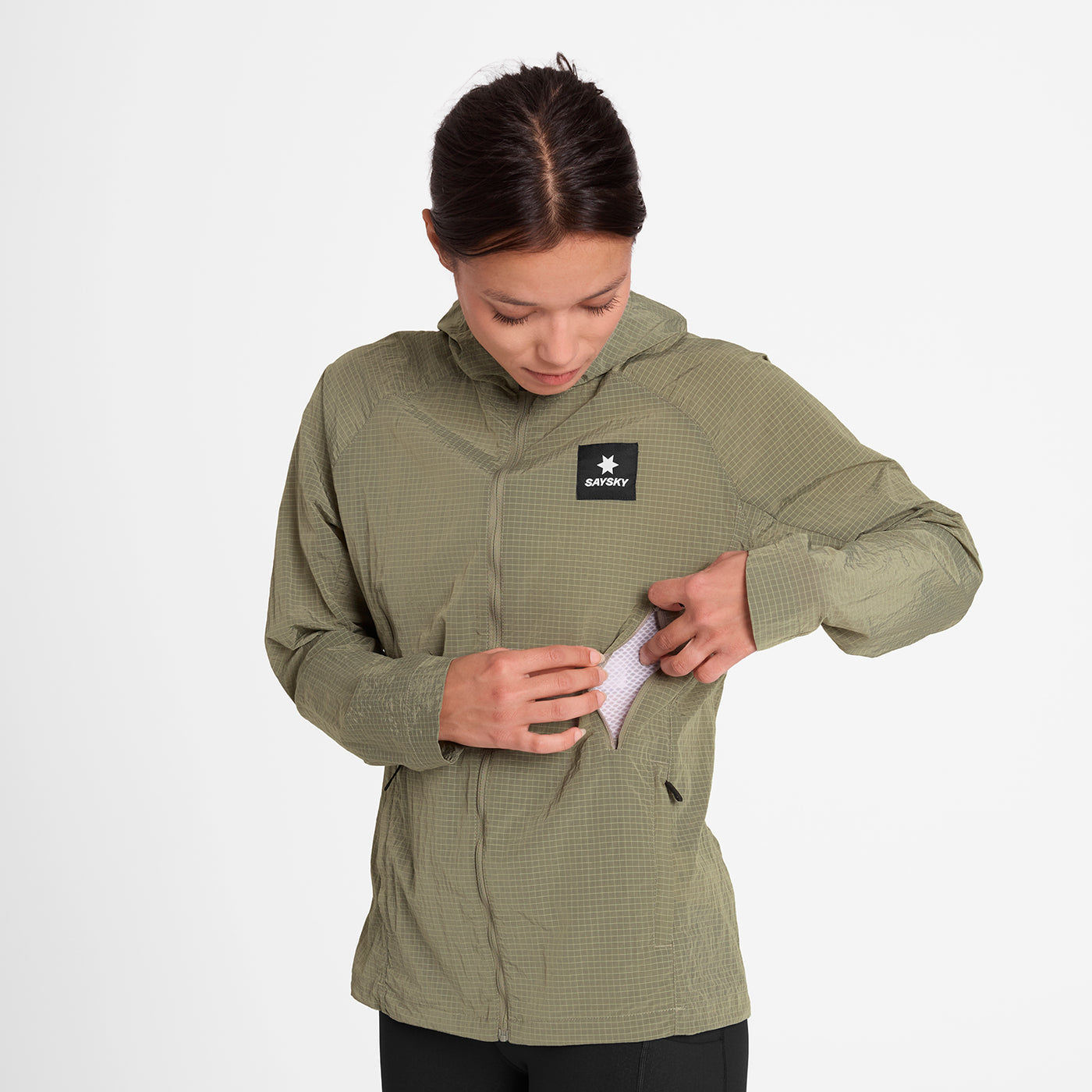 woman wearing SAYSKY running jacket in beige colour showing ventilation pocket