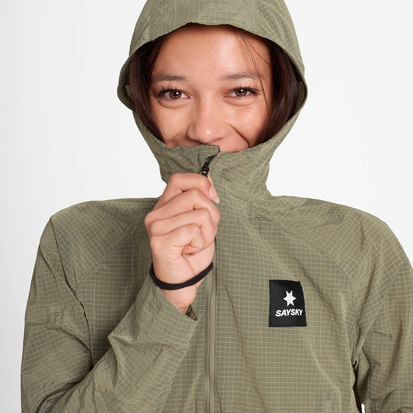 woman wearing SAYSKY running jacket in beige colour with hood up