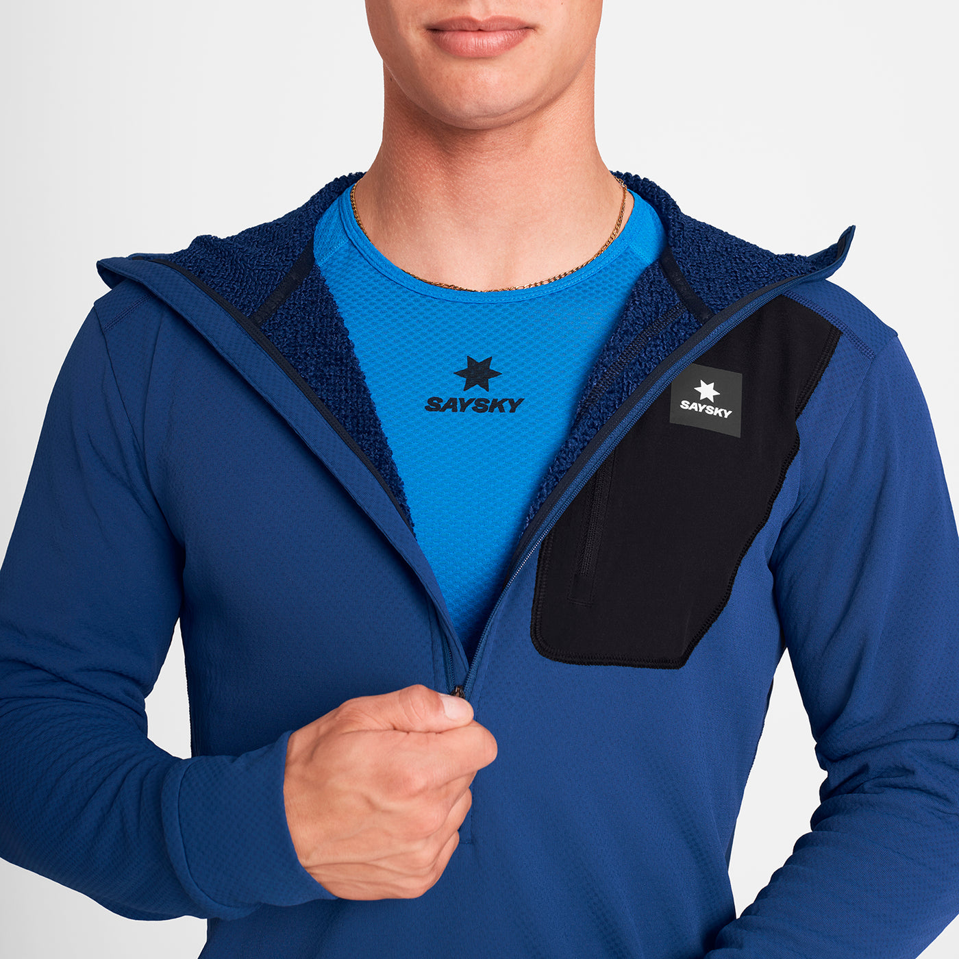 man wearing SAYSKY long sleeve, blue and black, fleece run top showing inner fleece material and zip