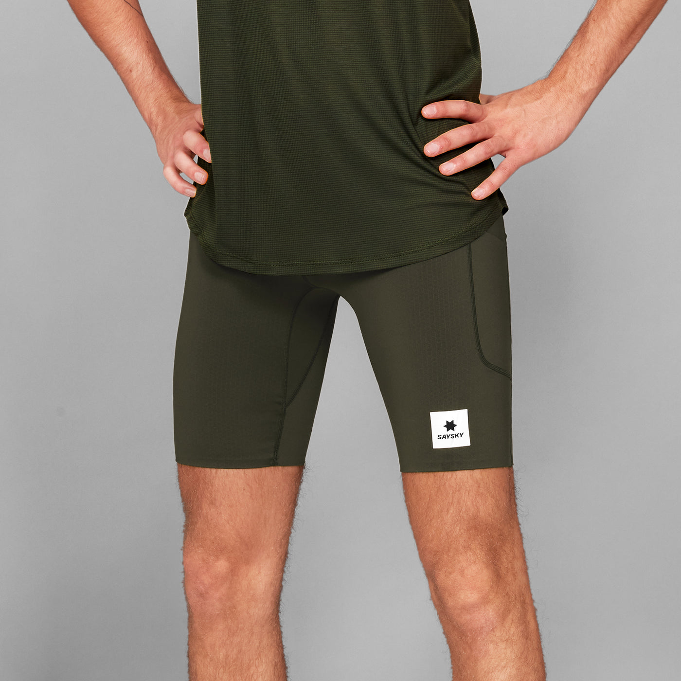 man wearing SAYSKY combat 9 inch run shorts in green, close up of logo