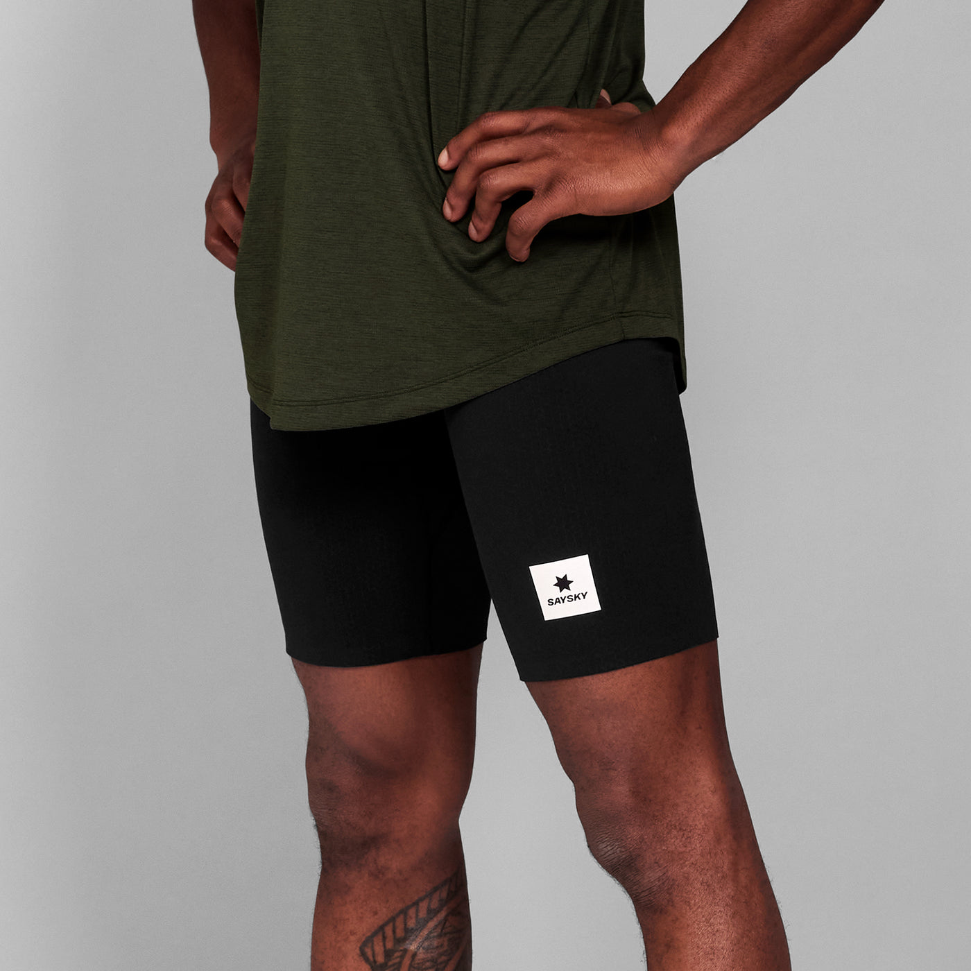 man wearing SAYSKY combat 9 inch run shorts in black, close up of logo