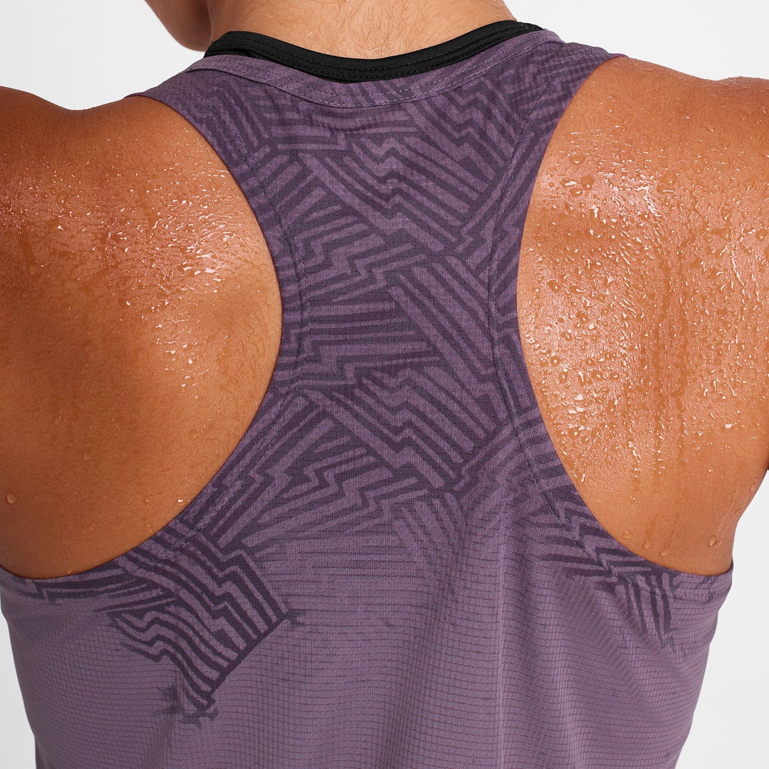 Woman wearing purple saysky run tank, reactive flow singlet showing back shape and hidden pattern when wet