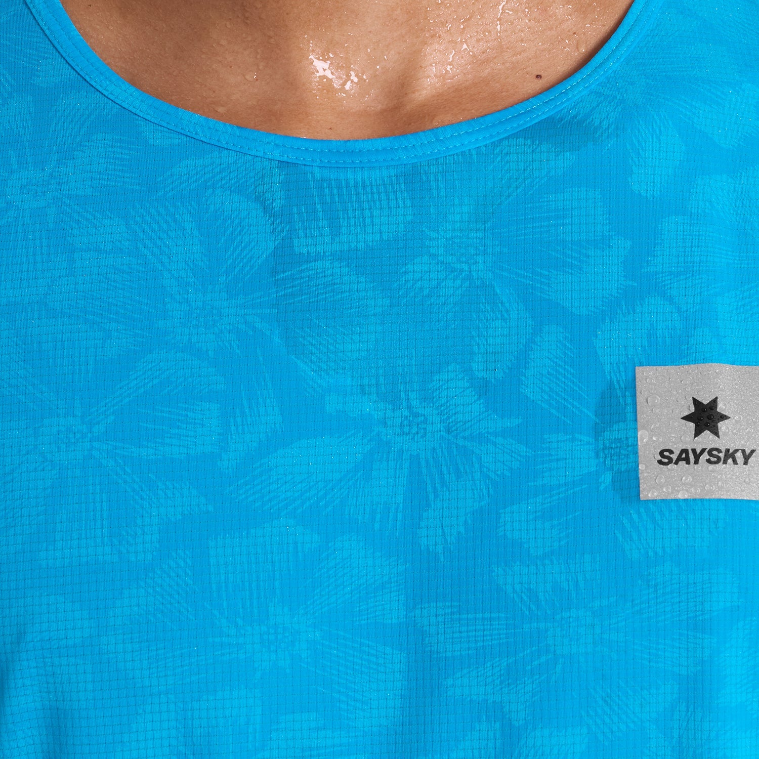 Close up of Blue SAYSKY Reactive run tee shirt, that throws out a flower pattern when wet