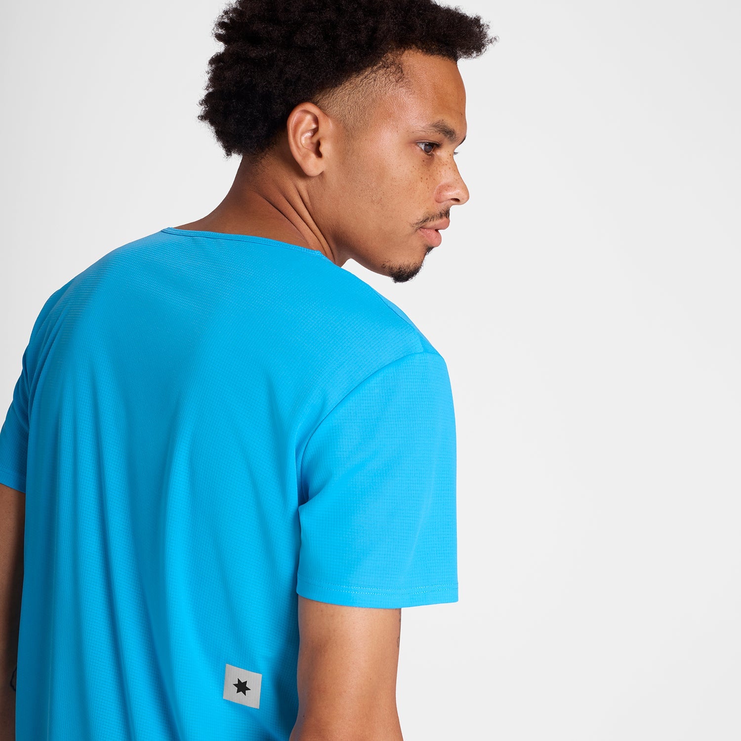 Man showing the back of Blue SAYSKY run tee shirt with star logo 