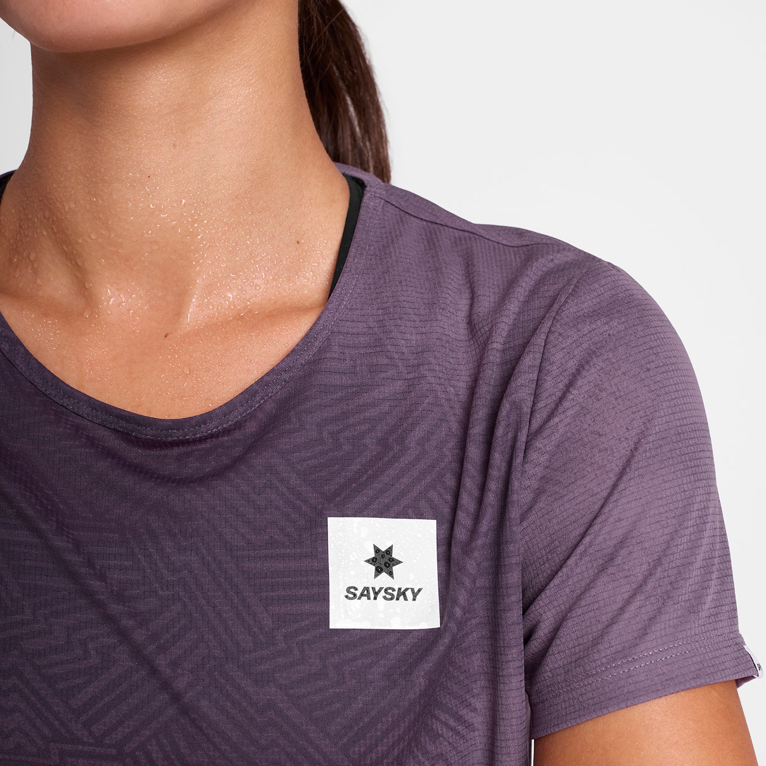 Woman wearing SAYSKY reactive women's run tee, purple colour,  showing hidden pattern when wet