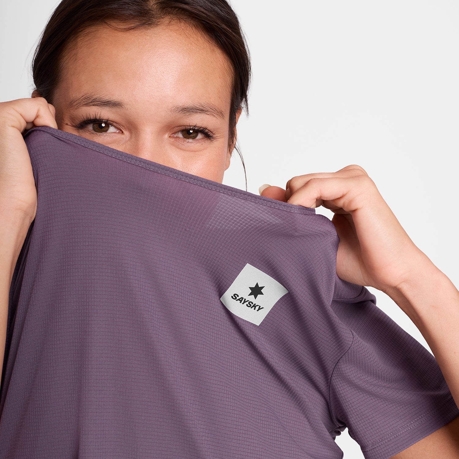 Woman wearing SAYSKY reactive women's run tee, purple colour, showing lightweight fabric