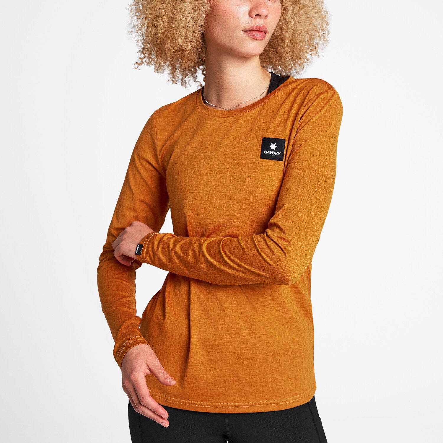 Woman wearing Orange SAYSKY long sleeve Pace run top 