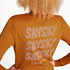 Woman showing the back of the orange SAYSKY long sleeve Pace run top 