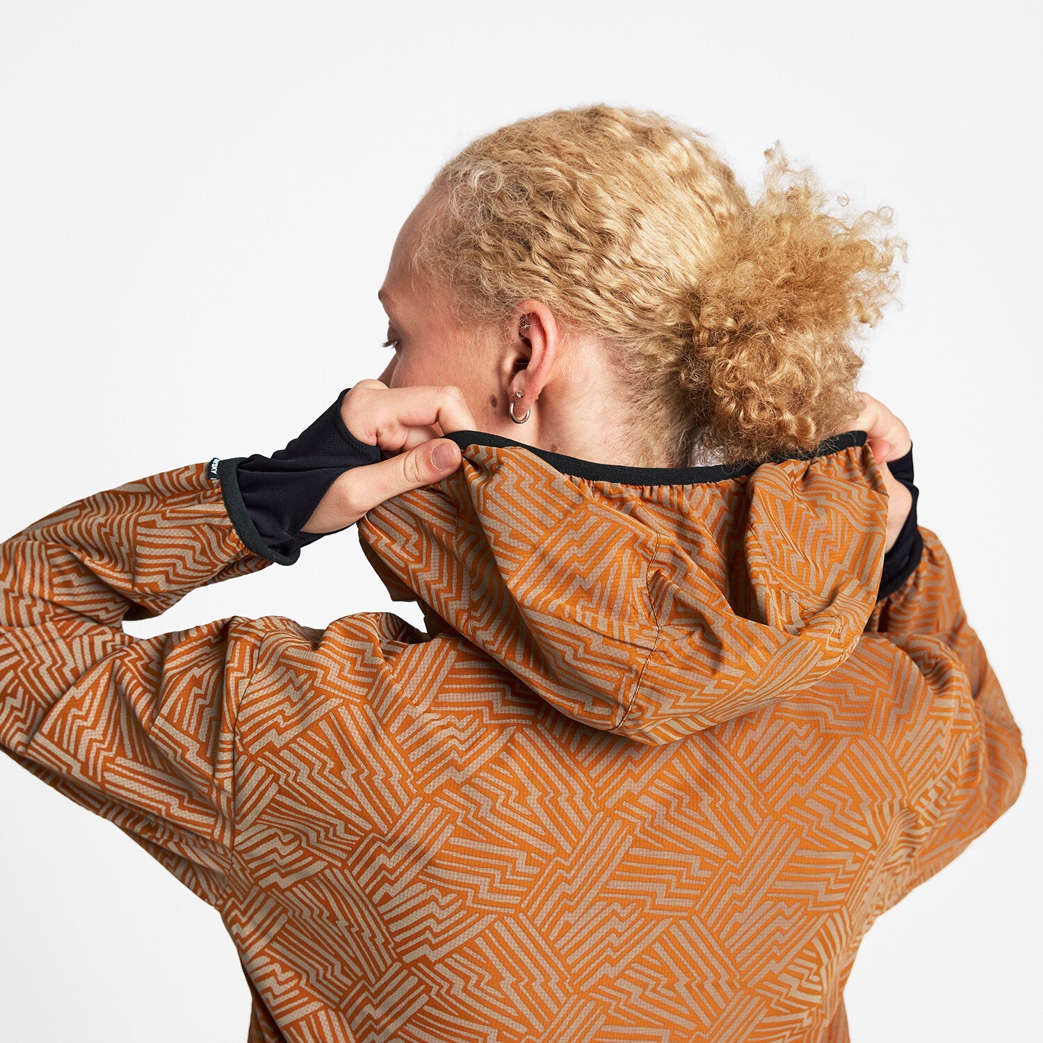 Woman wearing SAYSKY reflective blaze jacket in orange colour, showing close up of hood at back