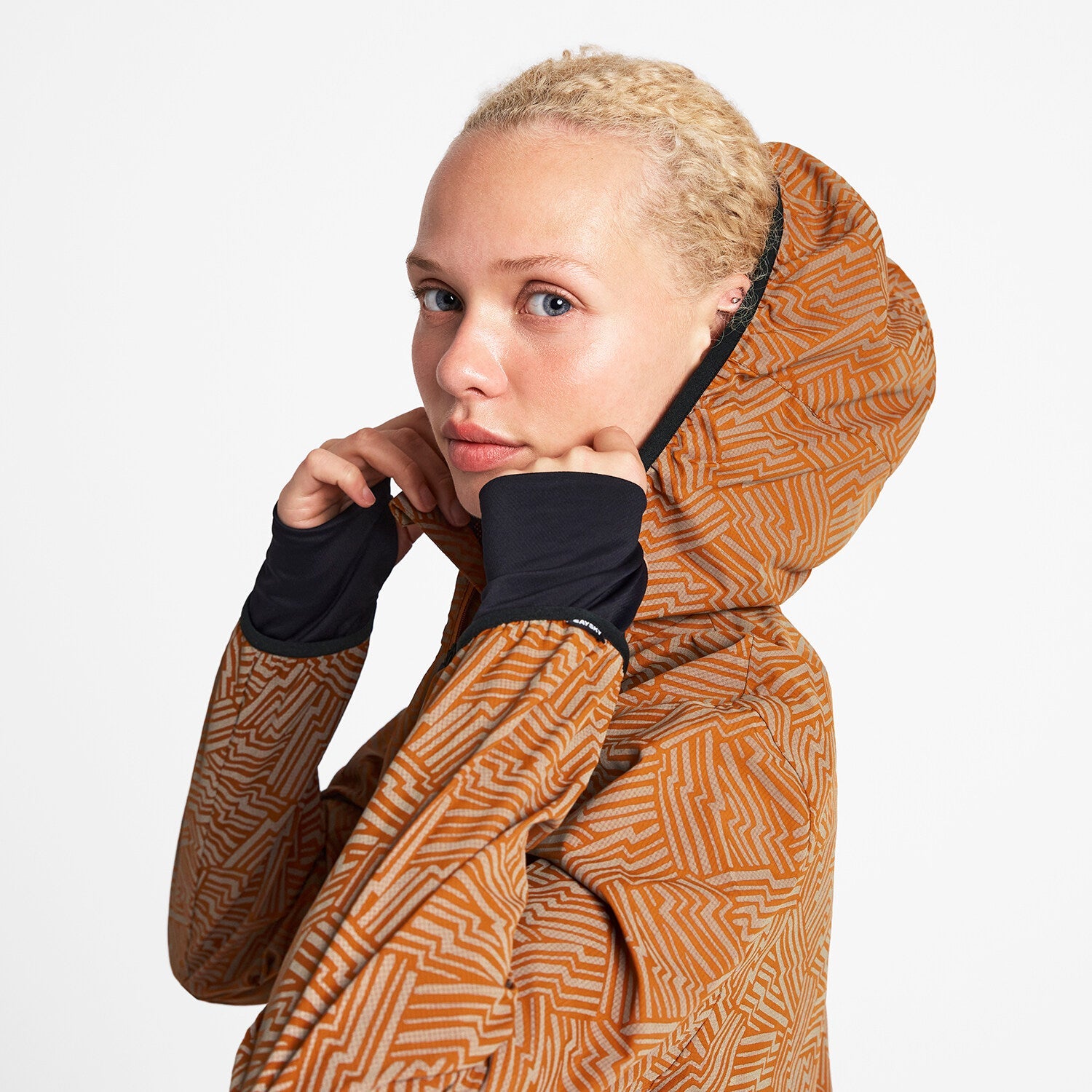 Woman wearing SAYSKY reflective blaze jacket in orange colour, showing hood and long cuffs