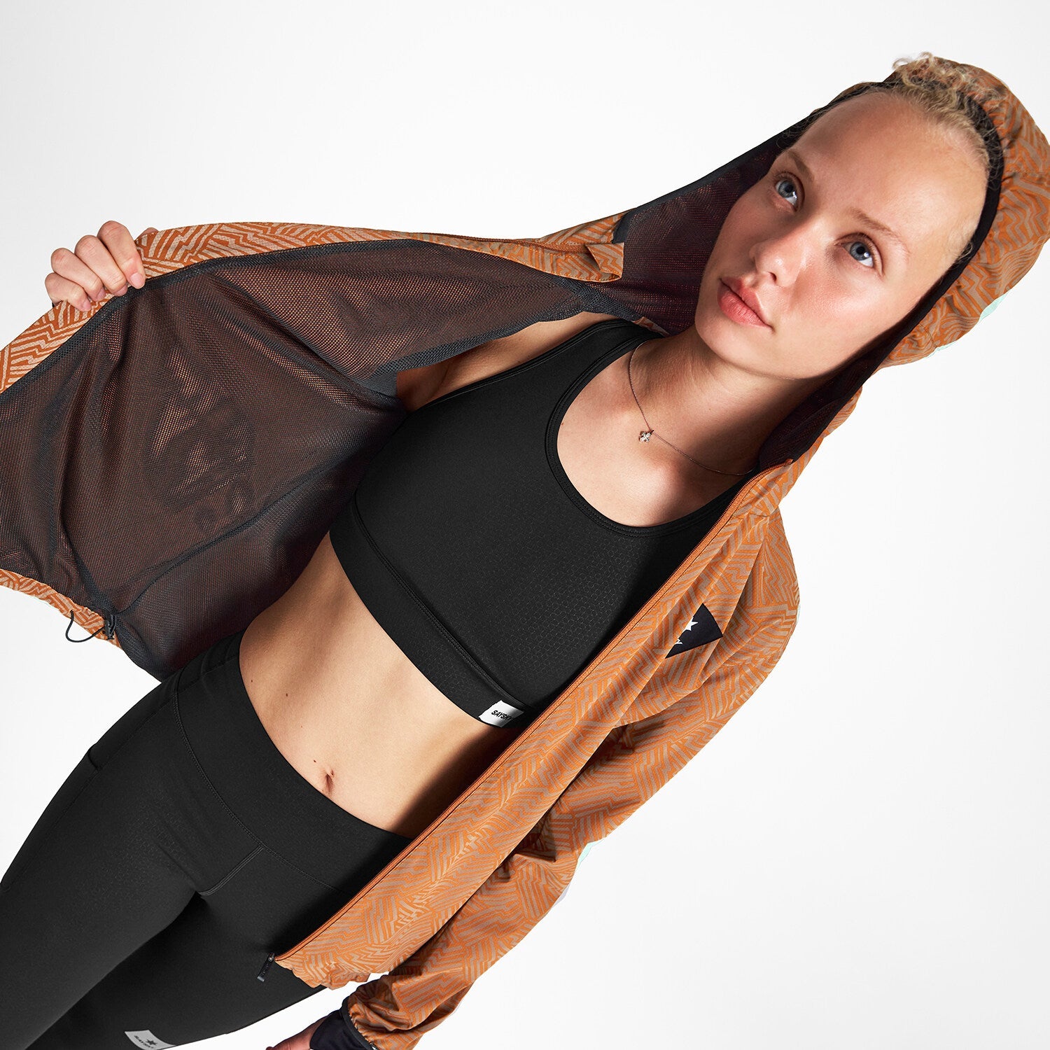 Woman wearing SAYSKY reflective blaze jacket in orange colour, showing inside lining