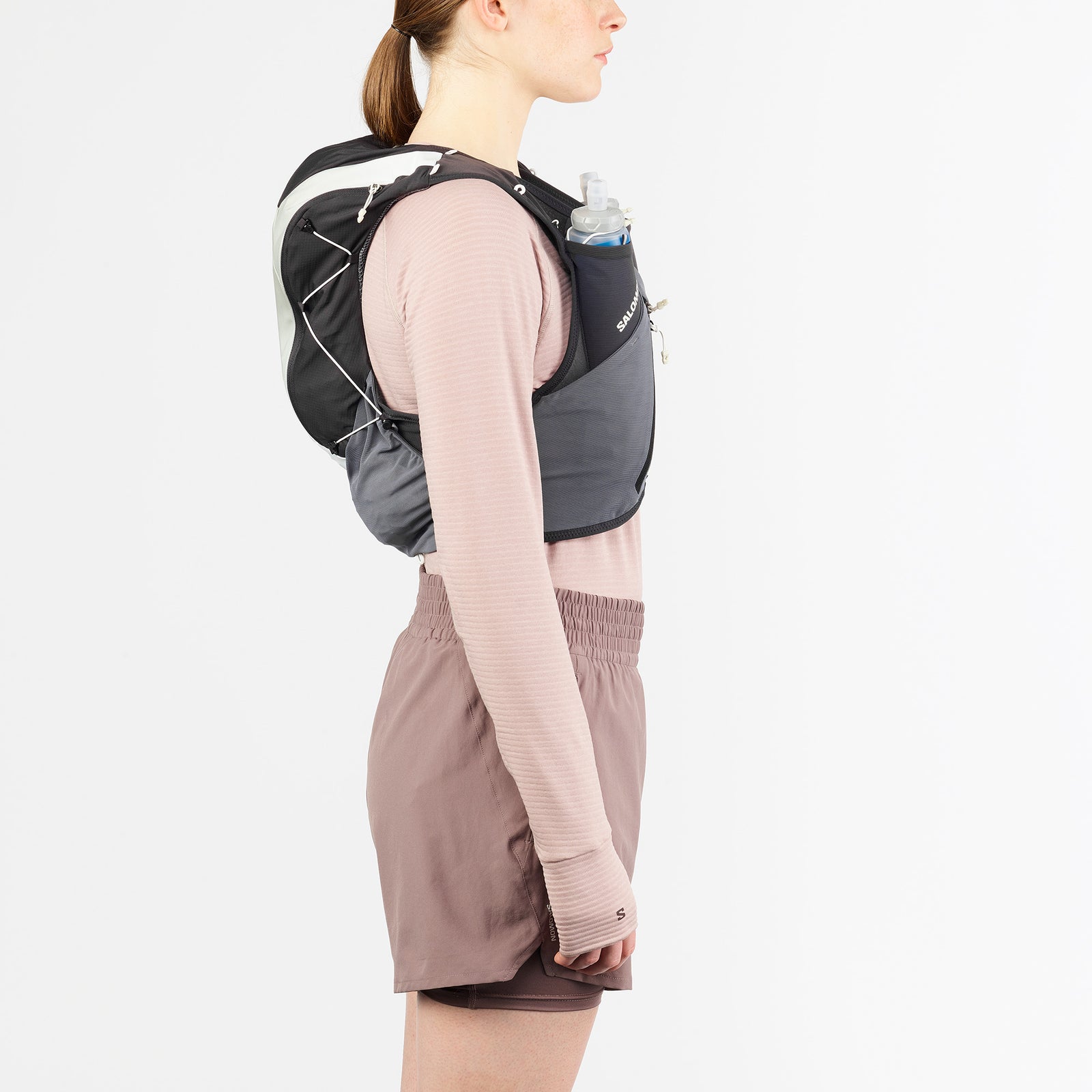 Salomon ADV Skin 12, 12 liter running vest, dark grey colour with dark green accents, woman wearing packed vest side profile