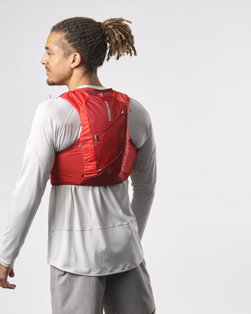 Man wearing salomon hydration vest for trail running, in red colour, back with Salomon logo