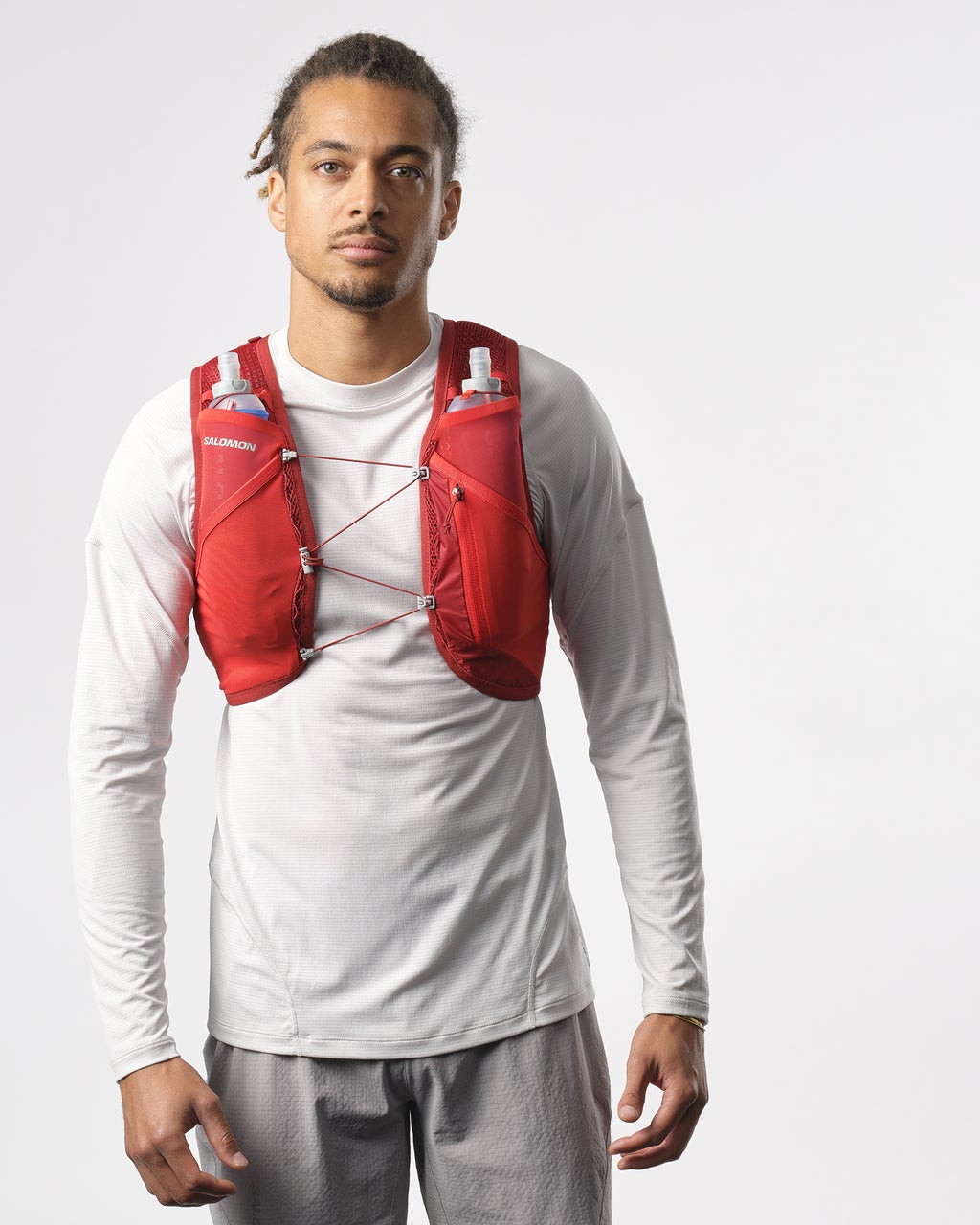 Man wearing salomon hydration vest for trail running, with flasks, in red colour,