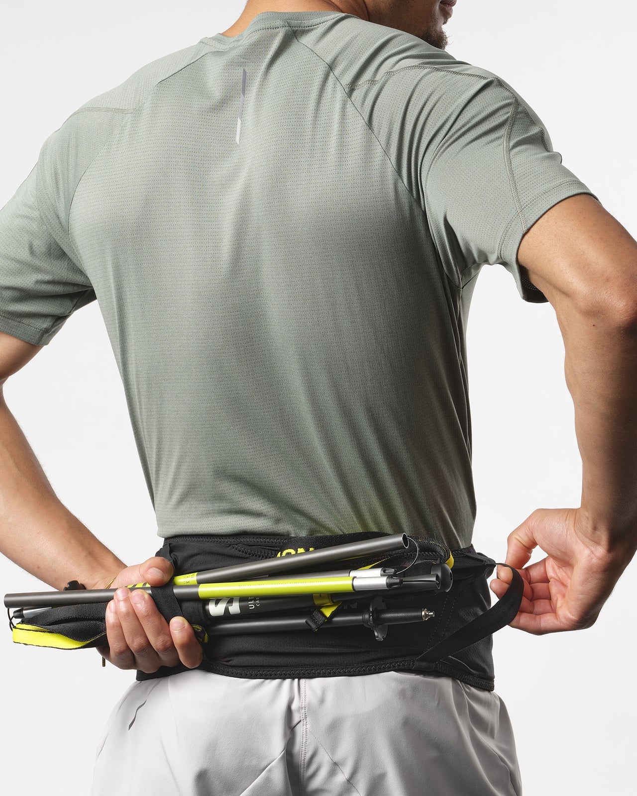 Man threading trail running poles through back of Salomon running belt