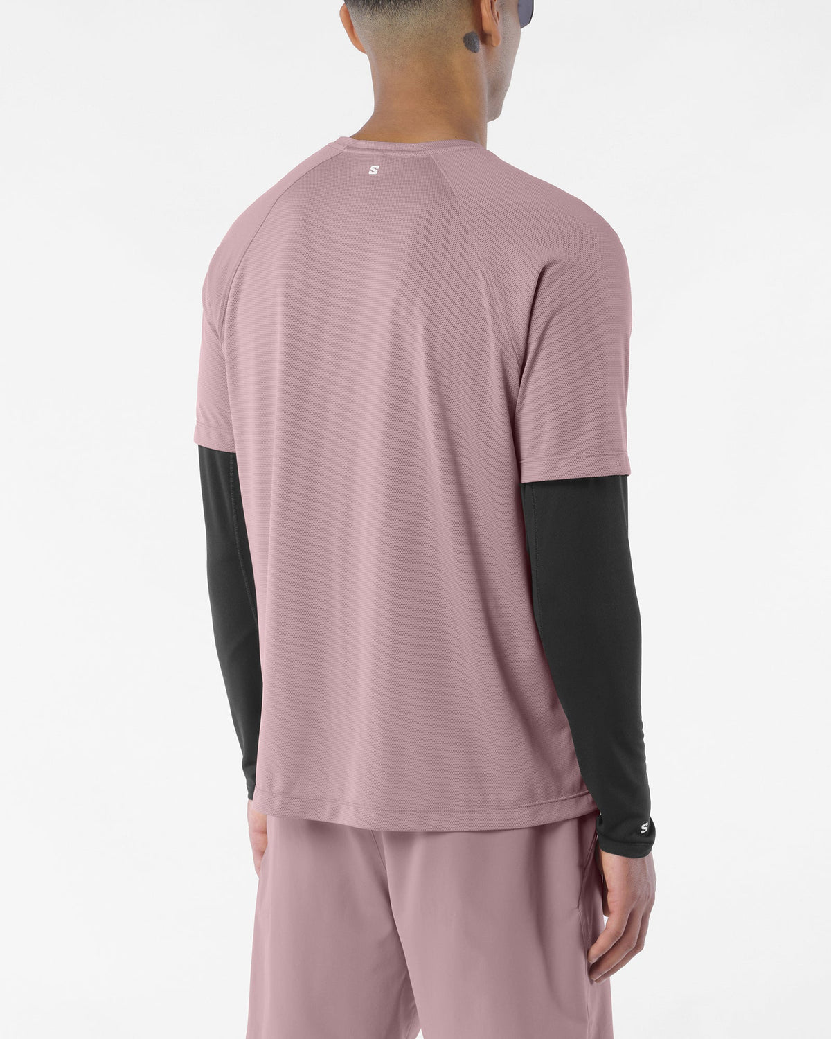 Man wearing salomon shakeout core tee in a pink colour, reflective logo on back