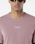 Close up of a an wearing salomon shakeout core tee in a pink colour, reflective logo on front