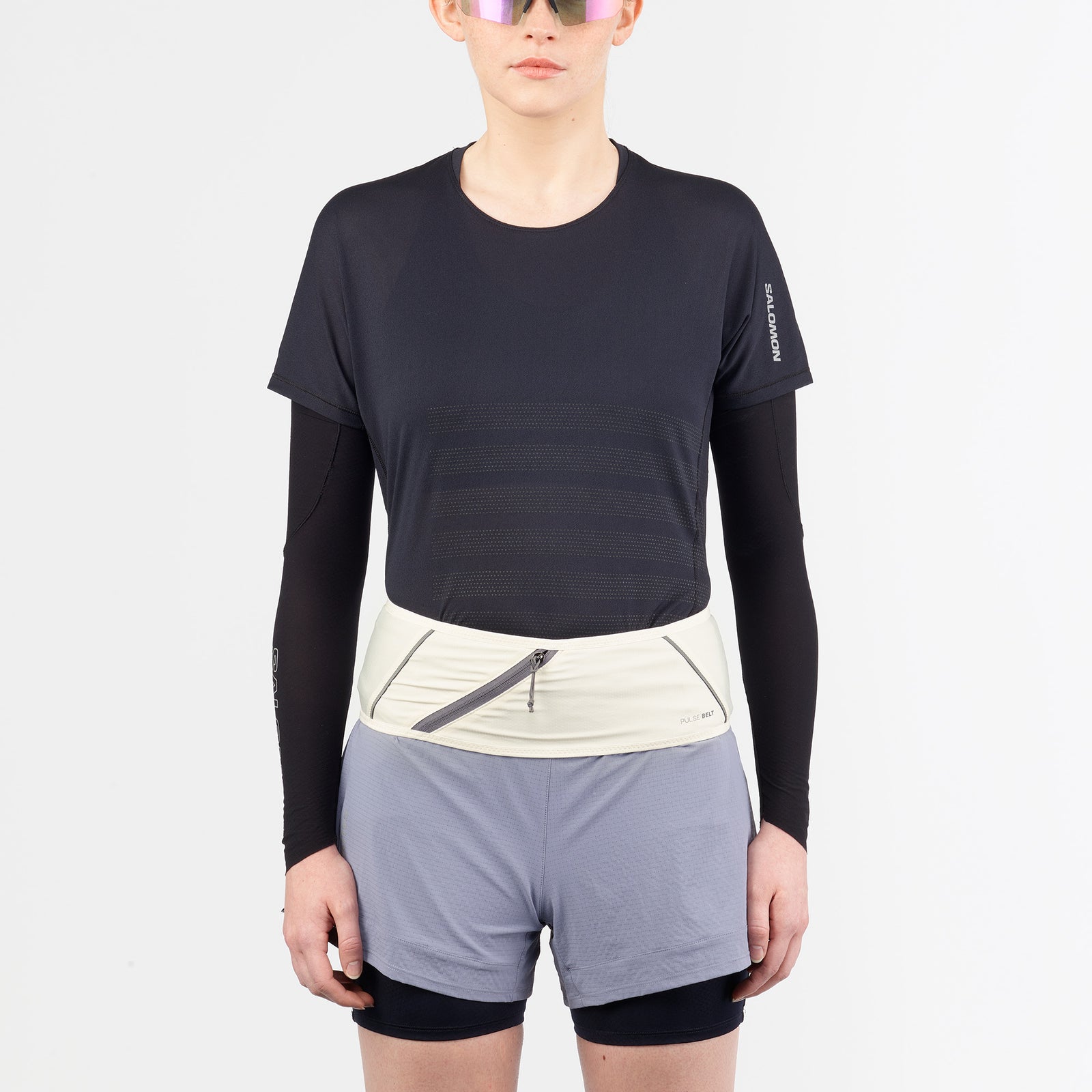salomon pulse belt, trail running belt with zipper pocket, cream white colour with grey details, women wearing belt from the front standing 