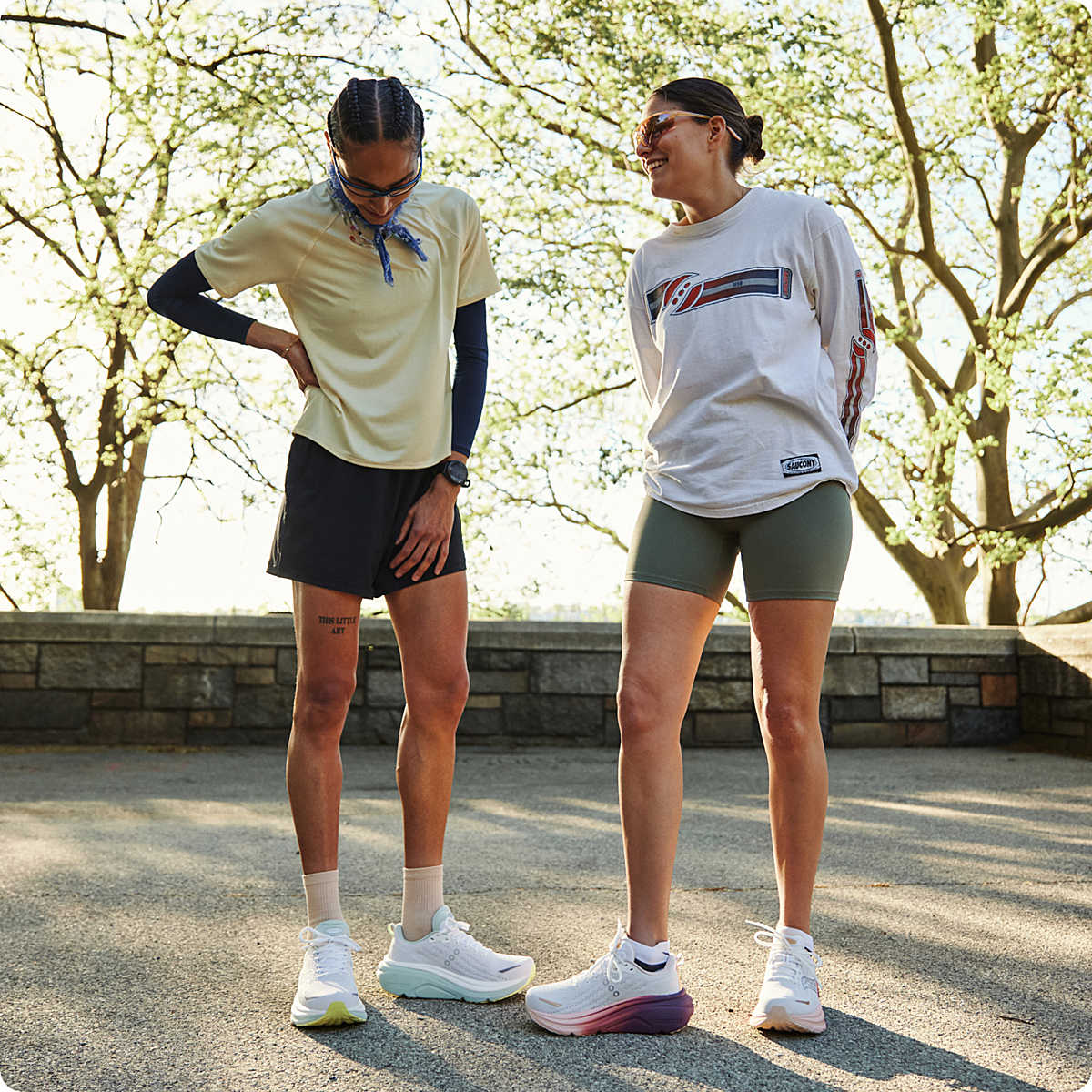 Two people in athletic wear standing outdoors with trees in the background and saucony hurricane on feet