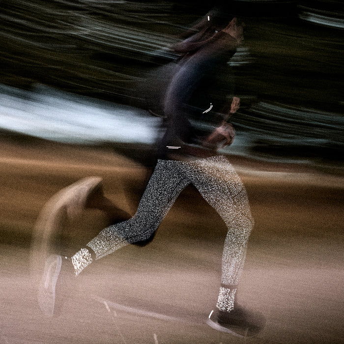 Person running on a track with reflective saysky socks and tights