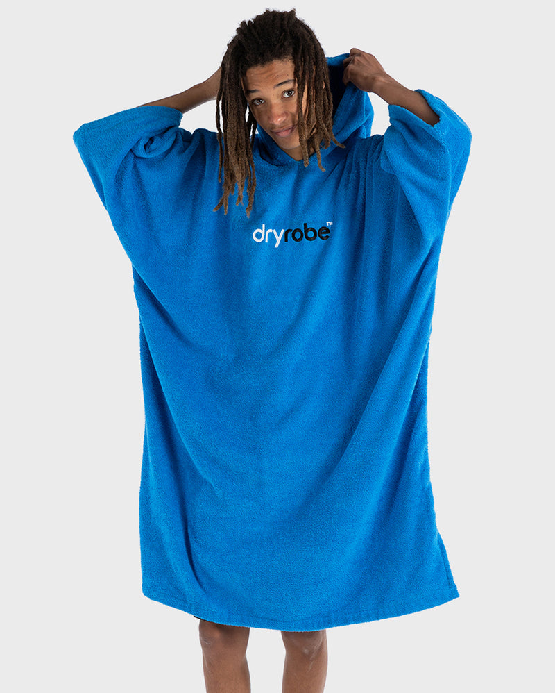 dryrobe organic cotton towel, towel changing robe for before and after swimming, cobalt blue colour, man wearing dryrobe towel pulling up the hood