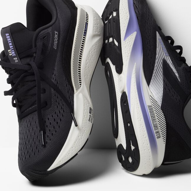 brooks adrenaline gts 24 for women, cushioned supportive running and walking shoe, black colour with silver logo white sole and purple details, pair of shoes angled against white wall with untied laces