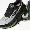 brooks cascadia 20 mens, road to trail gravel running and walking shoe, light grey and black with lime green details, one shoe sitting elevated ontop of a turned over one with untied laces