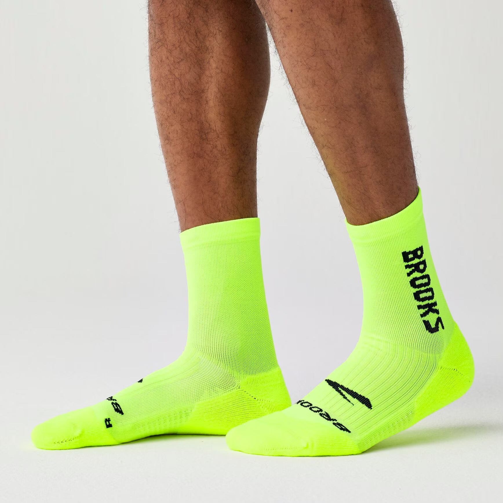 brooks ghost crew, maximum cushioning long run socks, neon green with black logo, person wear socks side profile 