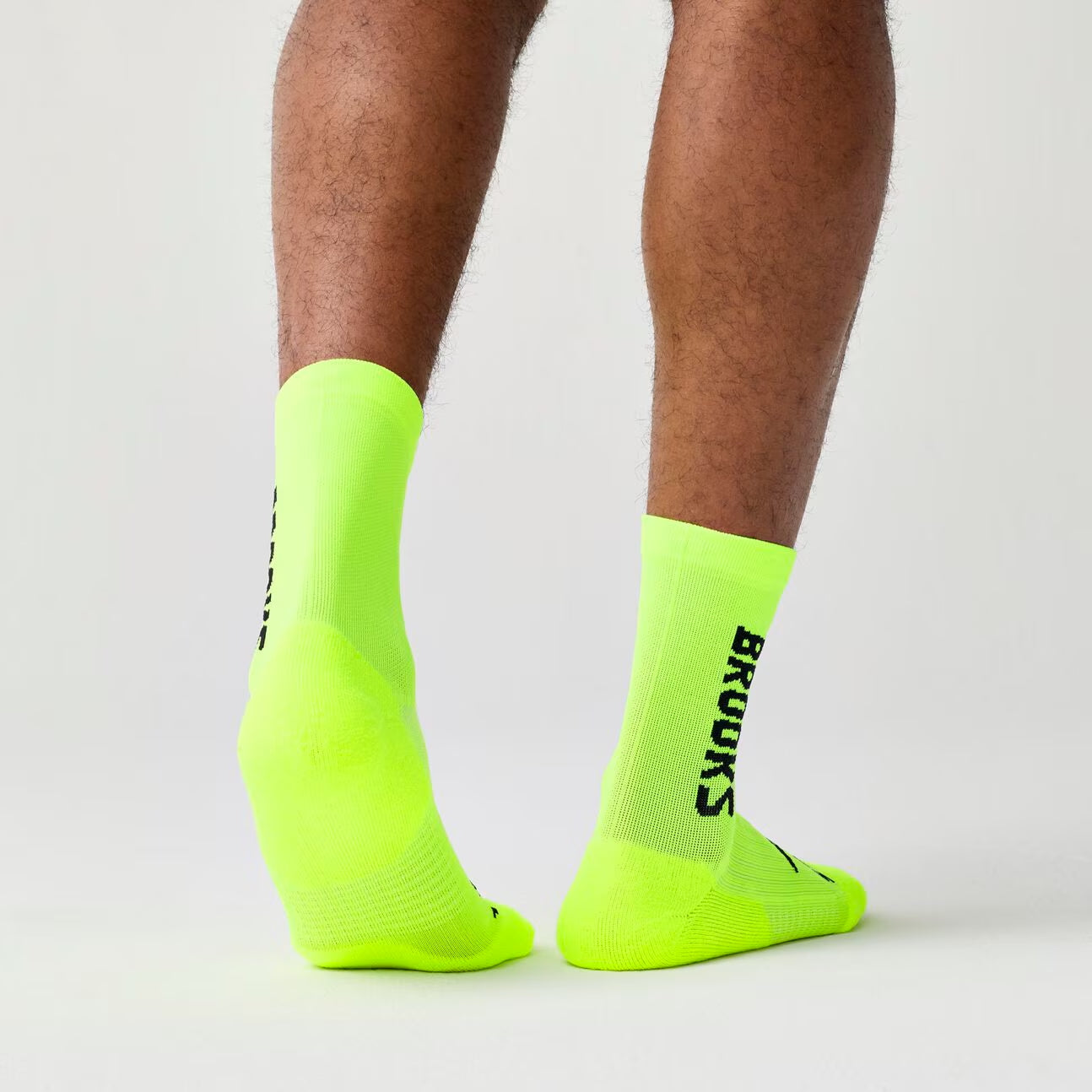 brooks ghost crew, maximum cushioning long run socks, neon green with black logo, person wear socks back of socks