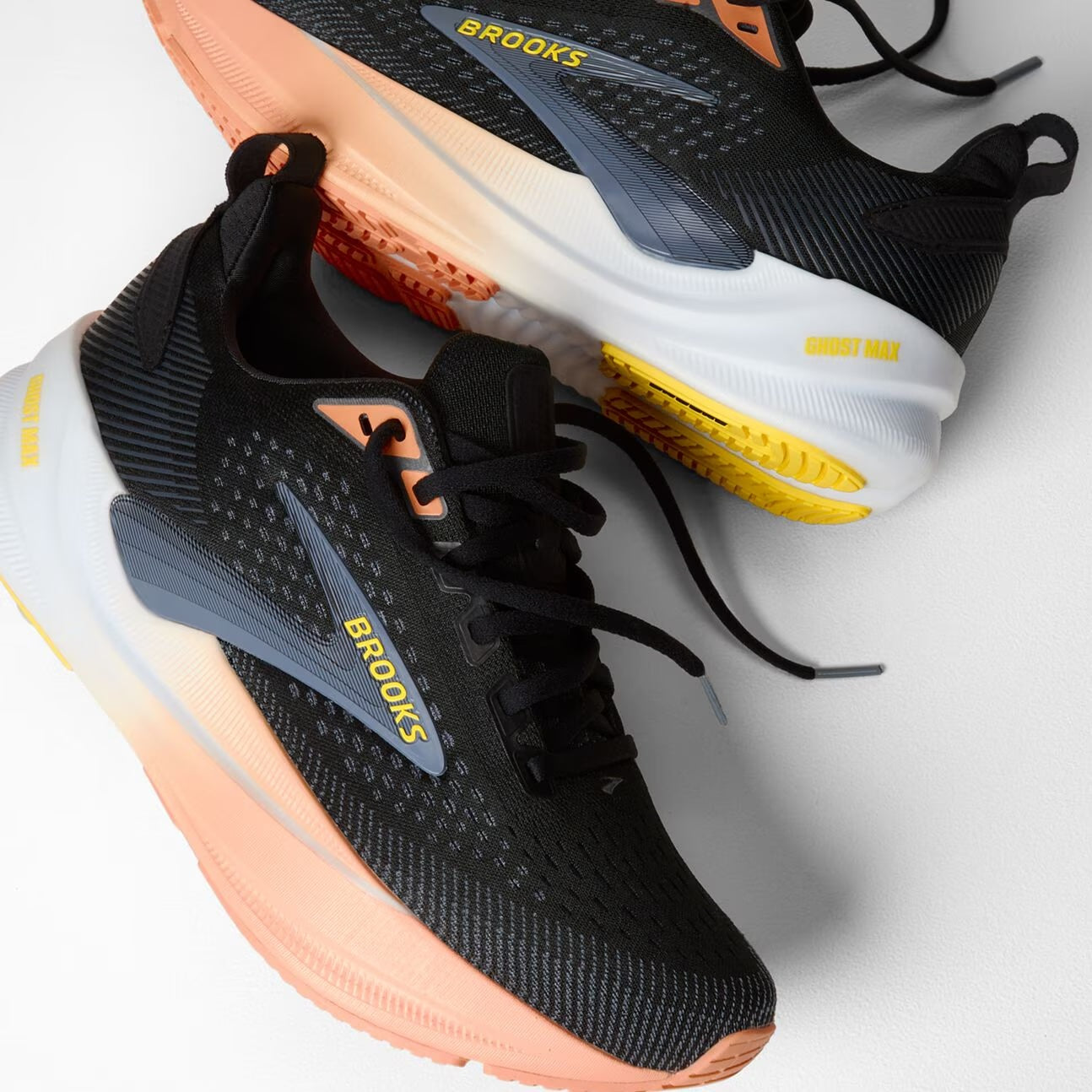 brooks ghost max 4 for women, long distance recovery or training running shoe with maximum protective cushioning, black with white and peach with yellow brooks logo, two shoes laid on side with untied laces