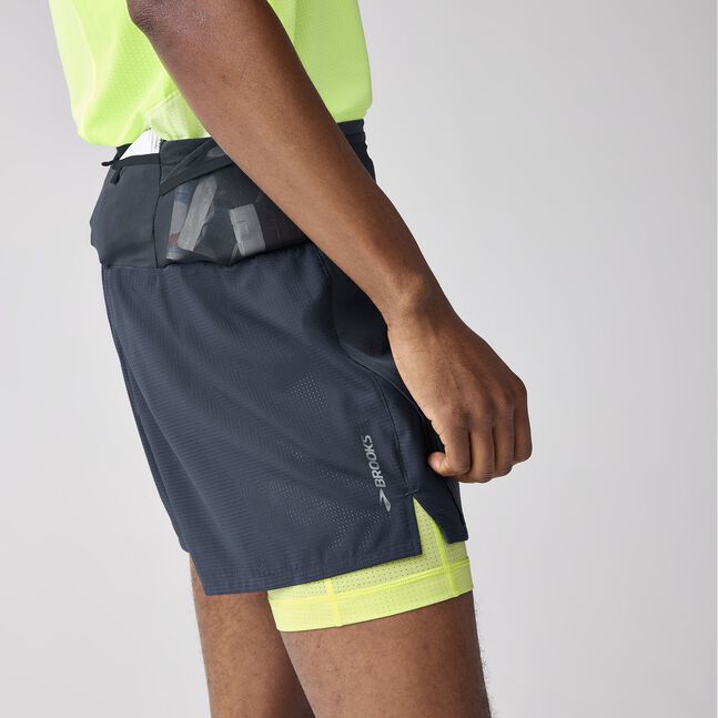 Man wearing Brooks High Point 2in1 trail shorts for men black and yellow colour