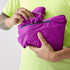 Woman showing how brooks high point waterproof running jacket is packable, purple, dark fuchsia colour