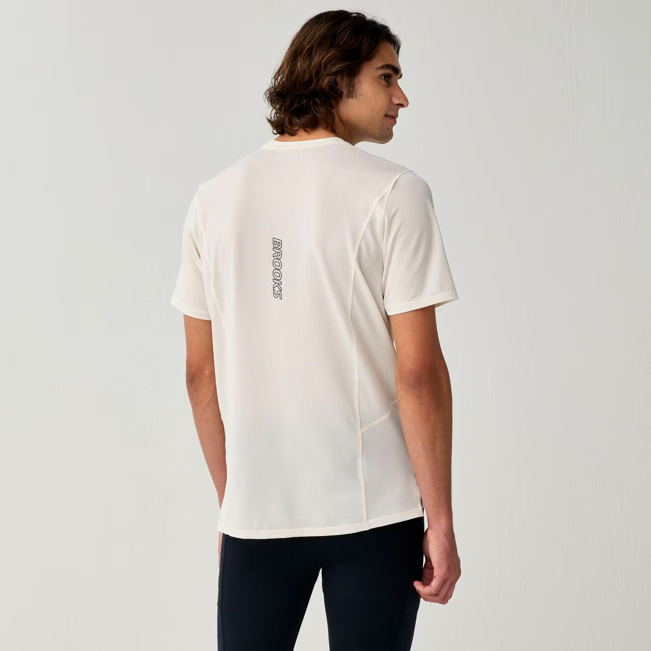 brooks high point short sleeve 2.0 for men, super lightweight and breathable trail running top, bone white colour, back view of man wearing brooks top with grey background