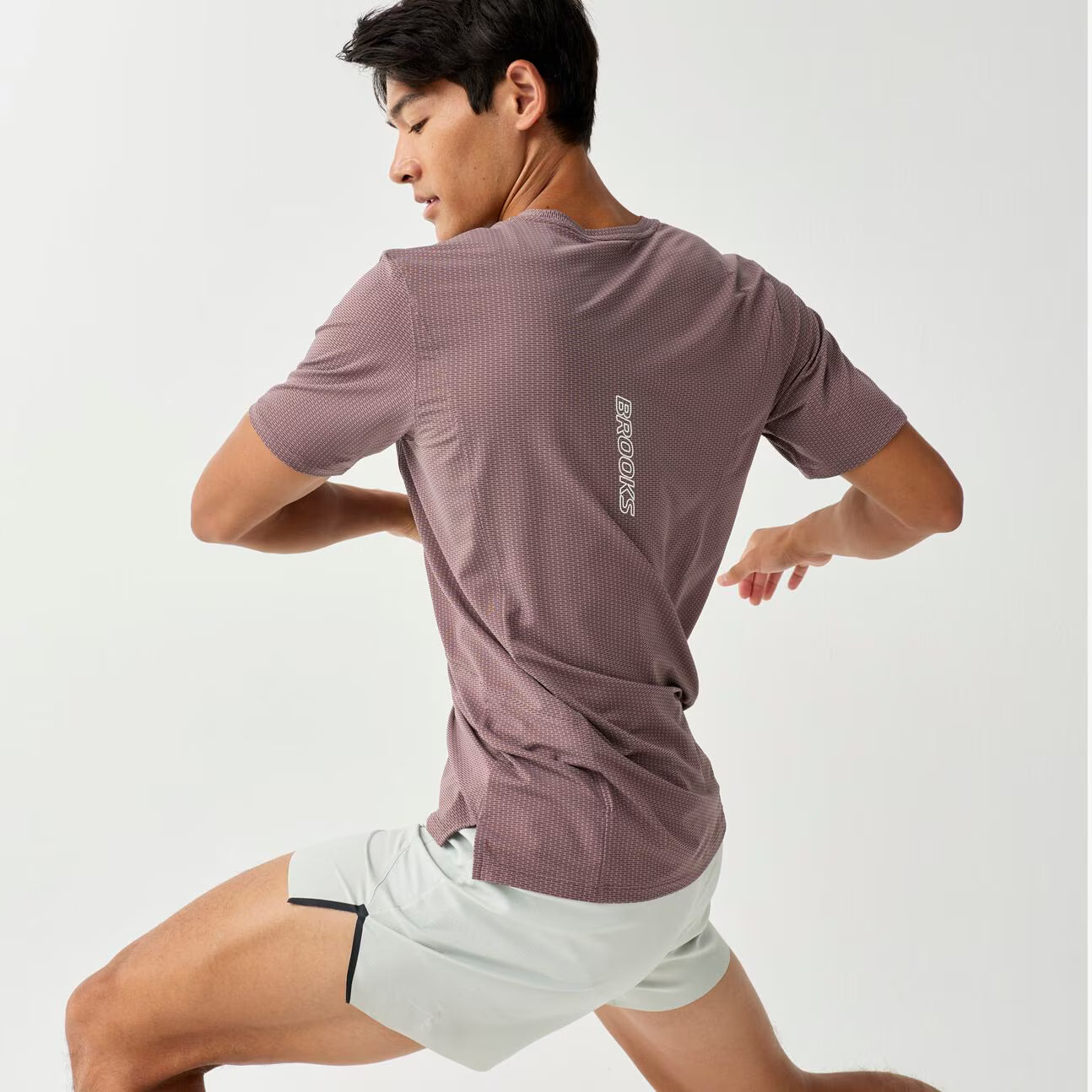 brooks high point short sleeve 2.0 for men, super lightweight and breathable trail running top, purple colour, man wearing brooks top with grey background